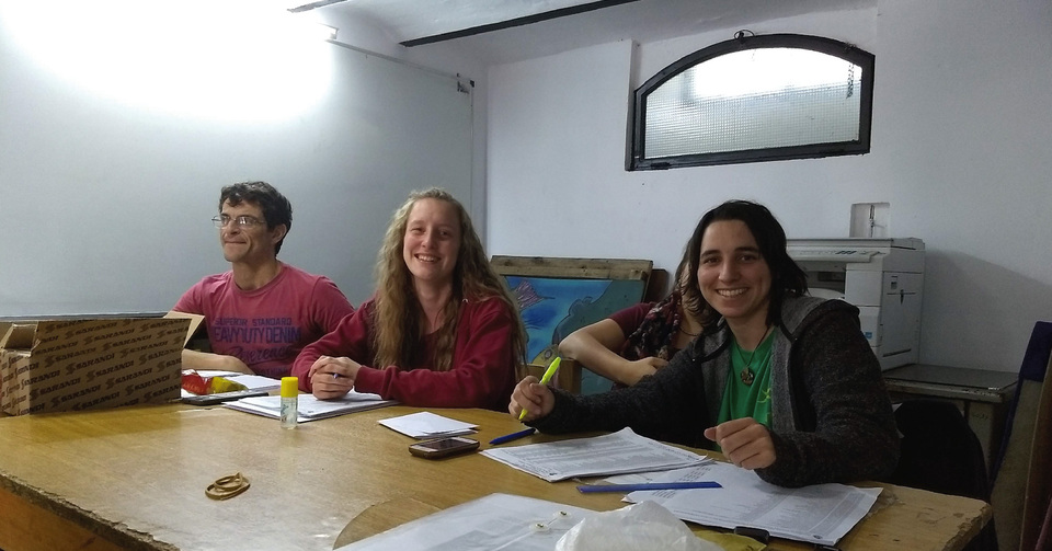 La imagen corresponde a representantes de las dos listas de Estudiantes, en  el Centro de Estudiantes. Hay una mesa con los padrones.