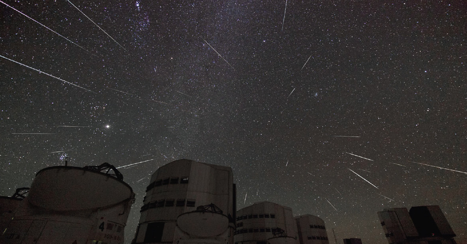 La imagen muestra los edificios del Observatorio Austral Europeo con todo el cielo nocturno atravesado por algunas estrellas fugaces.