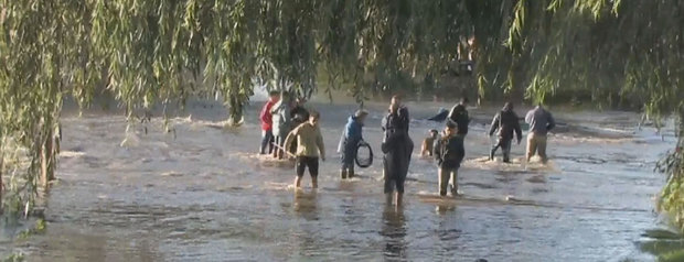 La imagen corresponde a una de las calles inundadas del barrio de Villa Elvira,con un grupo de vecinos con el agua a la altura de sus rodillas.